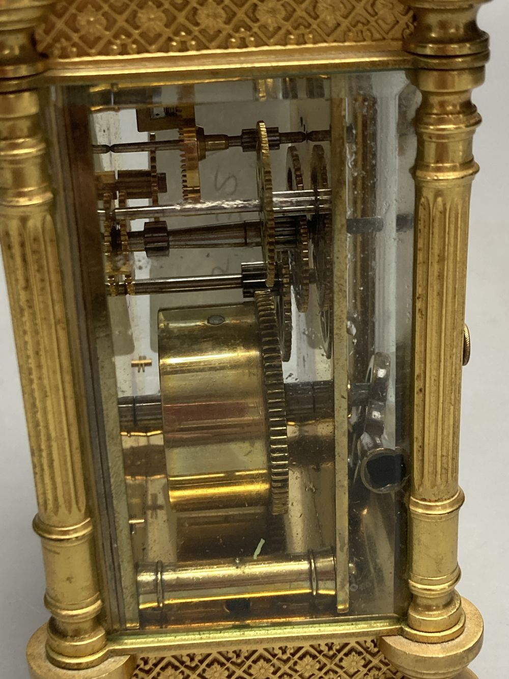 A brass timepiece with four glass panels and filigree decoration